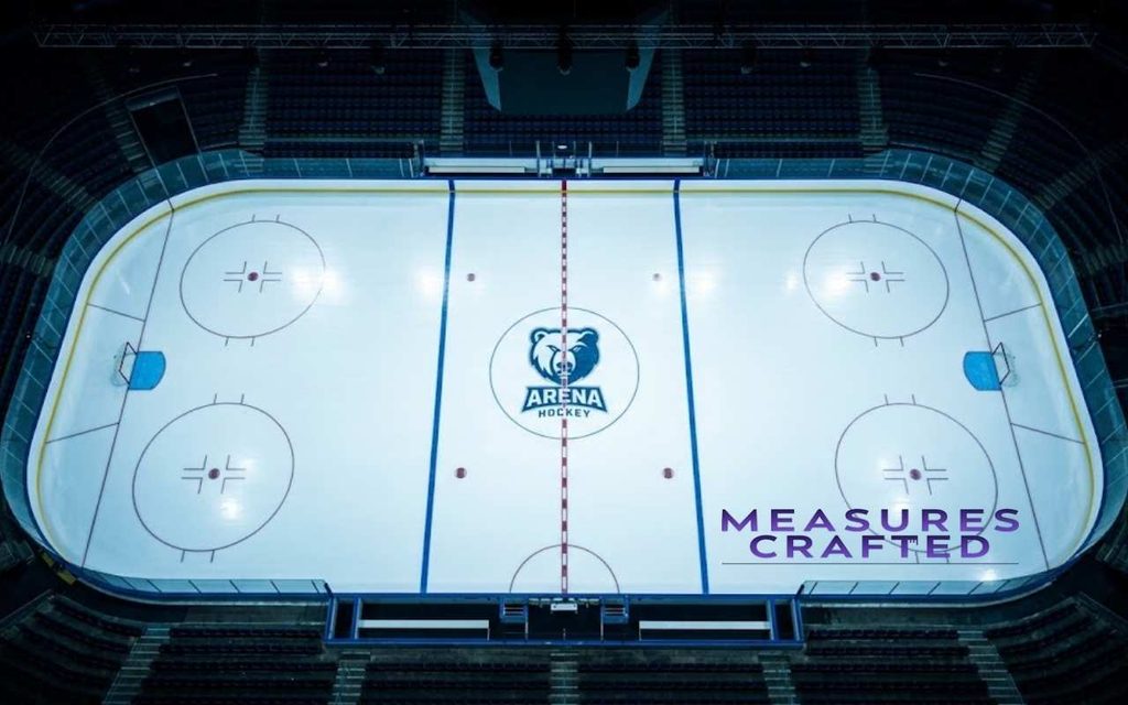 Overhead wide-angle shot of an empty indoor ice hockey rink illuminated beneath bright arena stadium lights.