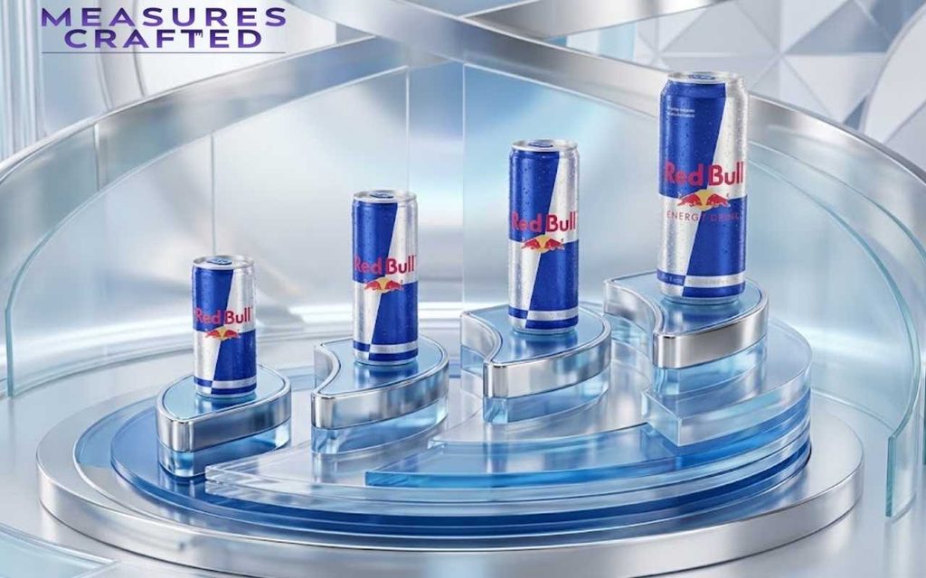 Four Red Bull cans of increasing size stand on reflective blue and chrome pedestals in a modern lab.